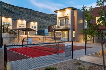 A pickleball court is located in front of a modern apartment complex.